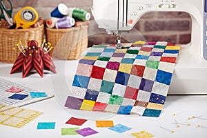 Colorful detail of quilt sewn from square pieces on sewing machine, quilting and sewing accessories