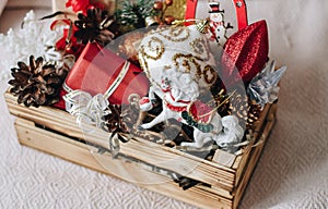 Colorful different Christmas toys and decor in the wooden gift box with horse, stars, cones, snowflake, snowman, gifts.