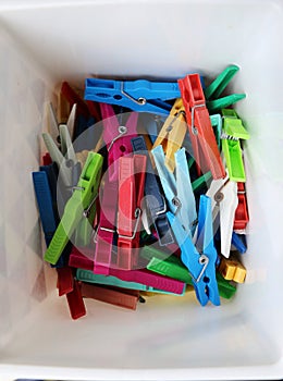 Heap of colorful clothespins are lying in a box