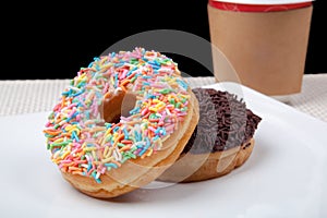 Colorful Donuts and coffee in white plate with black background