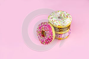 Colorful donuts with icing on pink background