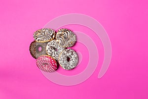 Colorful donuts with icing on pink background. Top view with copy space, realistic style