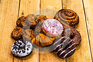 Colorful donuts on wooden table. Sweet icing sugar food with glazed sprinkles, doughnut with chocolate frosting. Top view with