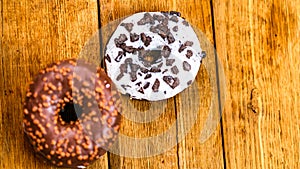 Colorful donuts on wooden table. Sweet icing sugar food with glazed sprinkles, doughnut with chocolate frosting. Top view with