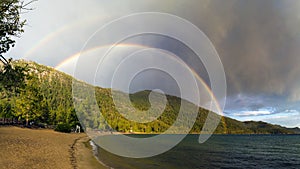 Colorful double rainbow over waves on Sand Harbor beach at Lake Tahoe Nevada