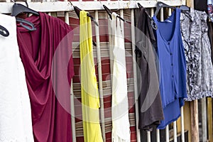 Colorful dresses hanged on metal bars that are ready to be sold near street