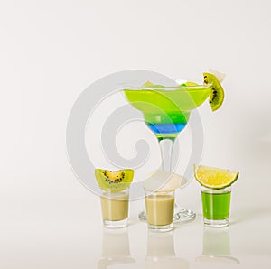 Colorful drink in a margarita glass, blue and green combination, many drinks in a shotglass