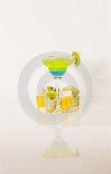 Colorful drink in a margarita glass, blue and green combination, many drinks in a shotglass