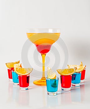 Colorful drink in a margarita glass, red and orange combination, seven drinks in a shotglass