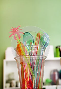 Colorful drinking straws in glass, plastic spoon and plastic spatula tool kitchenware for ice cream.