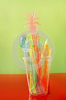 Colorful drinking straws in glass, plastic spoon and plastic spatula tool kitchenware for ice cream.