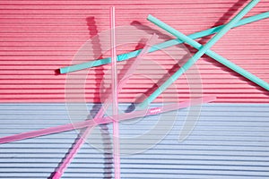 Colorful drinking straws on a pink and blue background, without a plastic Cup. Colorful summer background with Sunny shadows