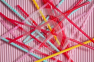 Colorful drinking straws on a pink and blue background, without a plastic Cup. Colorful summer background with Sunny shadows