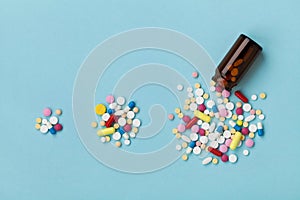 Colorful drug pills on blue background, increasing use and abuse of medication in world concept