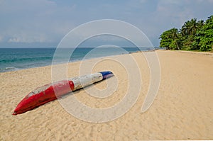 Colorful dugout fishing boat laying on deserted tropical beach at Robertsport, Liberia, West Africa