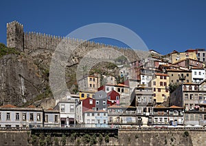 Colorful dwellings and a medieval wall along the Douro River in the Ribeira neighborhood of Porto, Portugal.