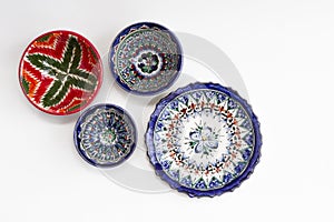 Colorful east ceramic plates and bowls with national pattern in blue and red colors isolated on white background, Tashkent,