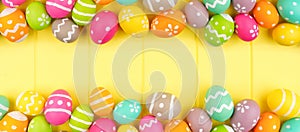 Colorful Easter banner with double border of Easter Eggs over a yellow wood background with copy space