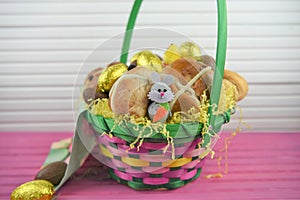 Golden foil chocolate eggs with cute Easter bunny decoration and hot cross buns