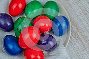 Colorful Easter chicken eggs painted in different colors lie on a white plate on the kitchen table. Concept of the holiday of