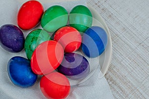 Colorful Easter chicken eggs painted in different colors lie on a white plate on the kitchen table. Concept of the holiday of