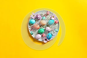 Colorful easter chicken and quail eggs with flowers on ceramic plate on yellow background