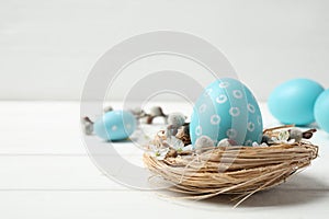 Colorful Easter egg in decorative nest on wooden table. Space for text