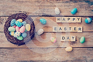 Colorful easter egg in the nest and wooden text of Happy Easter