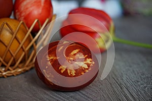 Colorful Easter egg and red tulip on a wooden table - close up view