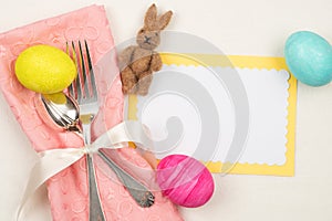 Colorful Easter Egg Table Setting with Silverware, Dyed eggs, Pink Napkin, Card on off white cloth