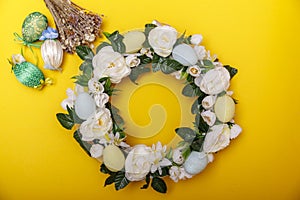 A colorful Easter egg wreath isolated over yellow background. Easter holiday concept with copyspace for text