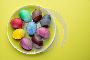 Colorful Easter eggs as an attribute of Easter celebration on the yellow plate