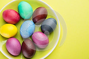 Colorful Easter eggs as an attribute of Easter celebration on the yellow plate