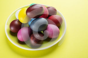 Colorful Easter eggs as an attribute of Easter celebration on the yellow plate