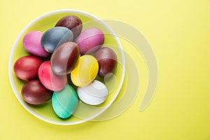 Colorful Easter eggs as an attribute of Easter celebration on the yellow plate