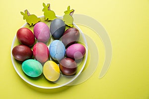 Colorful Easter eggs as an attribute of Easter celebration on the yellow plate