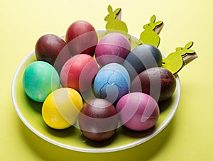 Colorful Easter eggs as an attribute of Easter celebration on the yellow plate