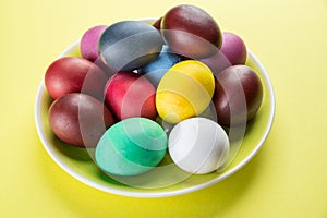 Colorful Easter eggs as an attribute of Easter celebration on the yellow plate