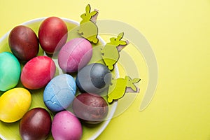 Colorful Easter eggs as an attribute of Easter celebration on the yellow plate