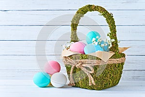 Colorful easter eggs in backet on a white wooden background