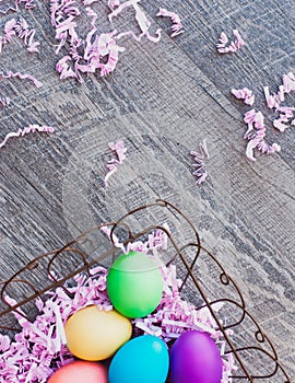Colorful Easter Eggs in Basket, against a Wood Floor Backdrop.