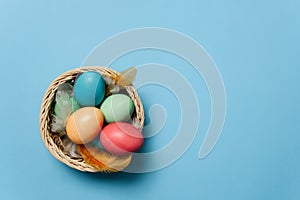 Colorful Easter eggs in a basket among feathers