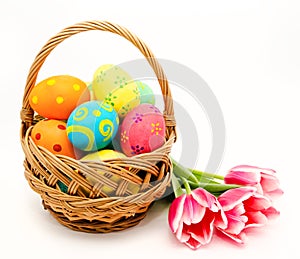 Colorful easter eggs in basket and flowers isolated on a white