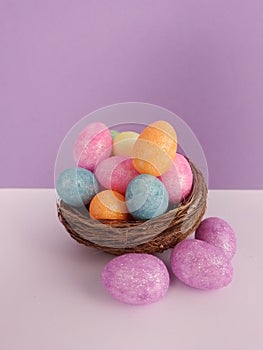 Colorful Easter eggs in a birds nest on a purple and white background