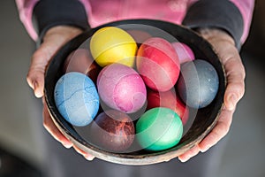 Colorful Easter eggs in bowl in woman`s hands