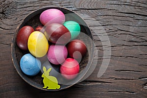 Colorful Easter eggs in bowl on wooden table. Attribute of Easter celebration