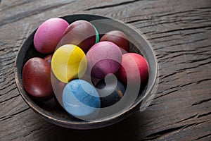 Colorful Easter eggs in bowl on wooden table. Attribute of Easter celebration