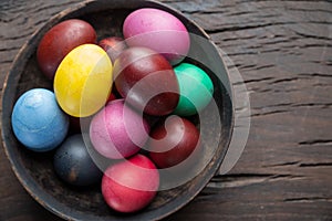 Colorful Easter eggs in bowl on wooden table. Attribute of Easter celebration