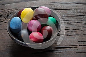 Colorful Easter eggs in bowl on wooden table. Attribute of Easter celebration
