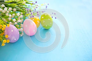 Colorful easter eggs and branch with flowers on blue wooden desk